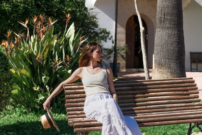 Junge Frau entspannt auf einer Holzbank im Garten der Son Manera Retreat Finca